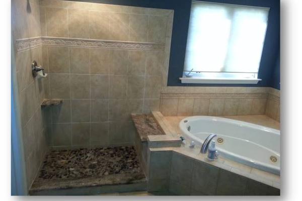 A luxurious custom-built master bathroom showcasing a separate bathtub and shower arrangement. The bathtub, adorned with elegant tile surroundings, invites relaxation with its deep soaking design. Custom lighting fixtures illuminate the space, creating a serene ambiance for unwinding and rejuvenation. This project was completed by Applause Plumbing and Heating for a customer in Forks, Pennsylvania.