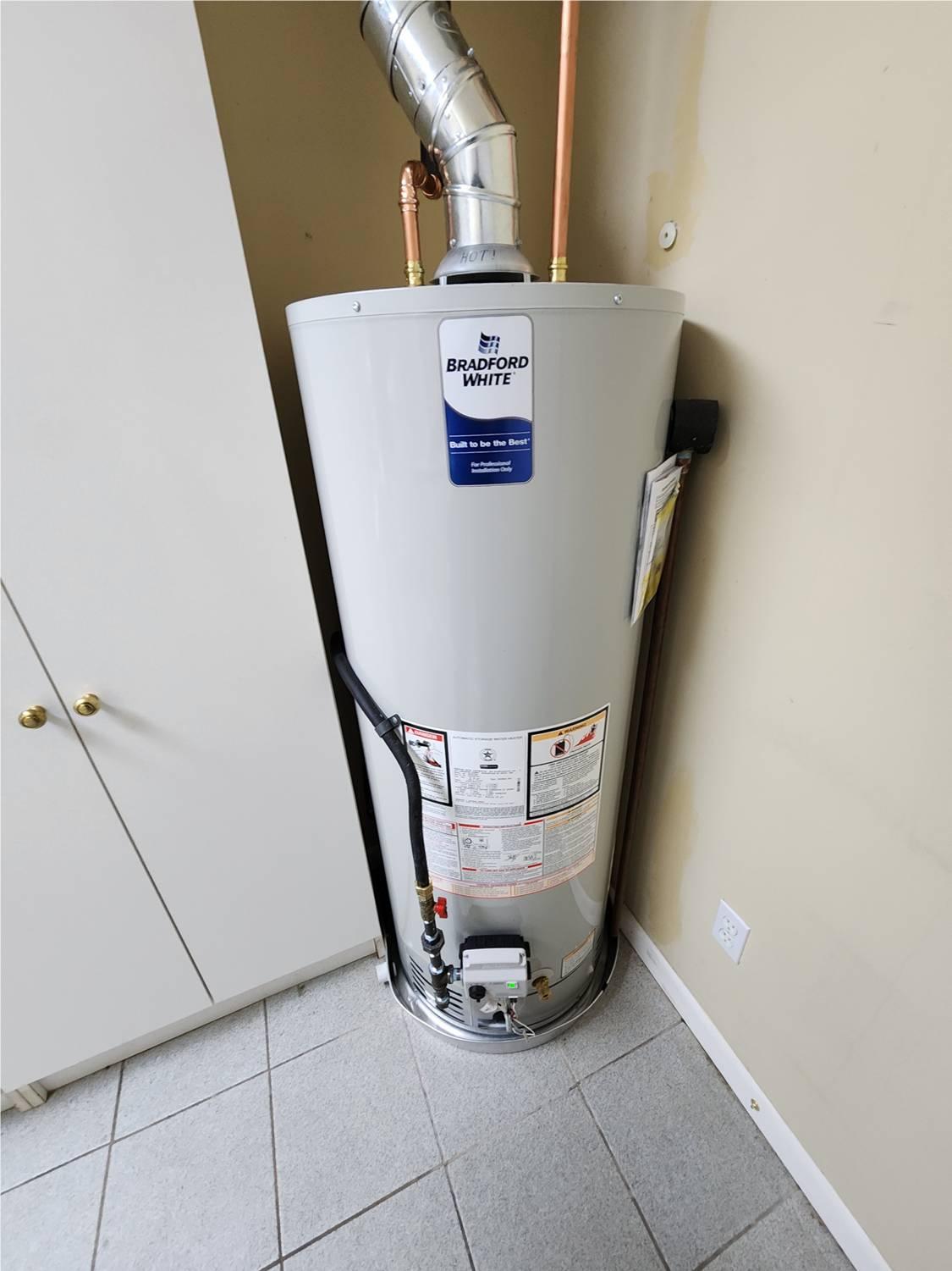 A newly installed 50-gallon Bradford White natural gas water heater, complete with a drain pan for leak protection and a chimney flue for safe venting. Professionally installed by Applause Plumbing and Heating in Stewartsville, NJ, ensuring reliable hot water for the homeowner.